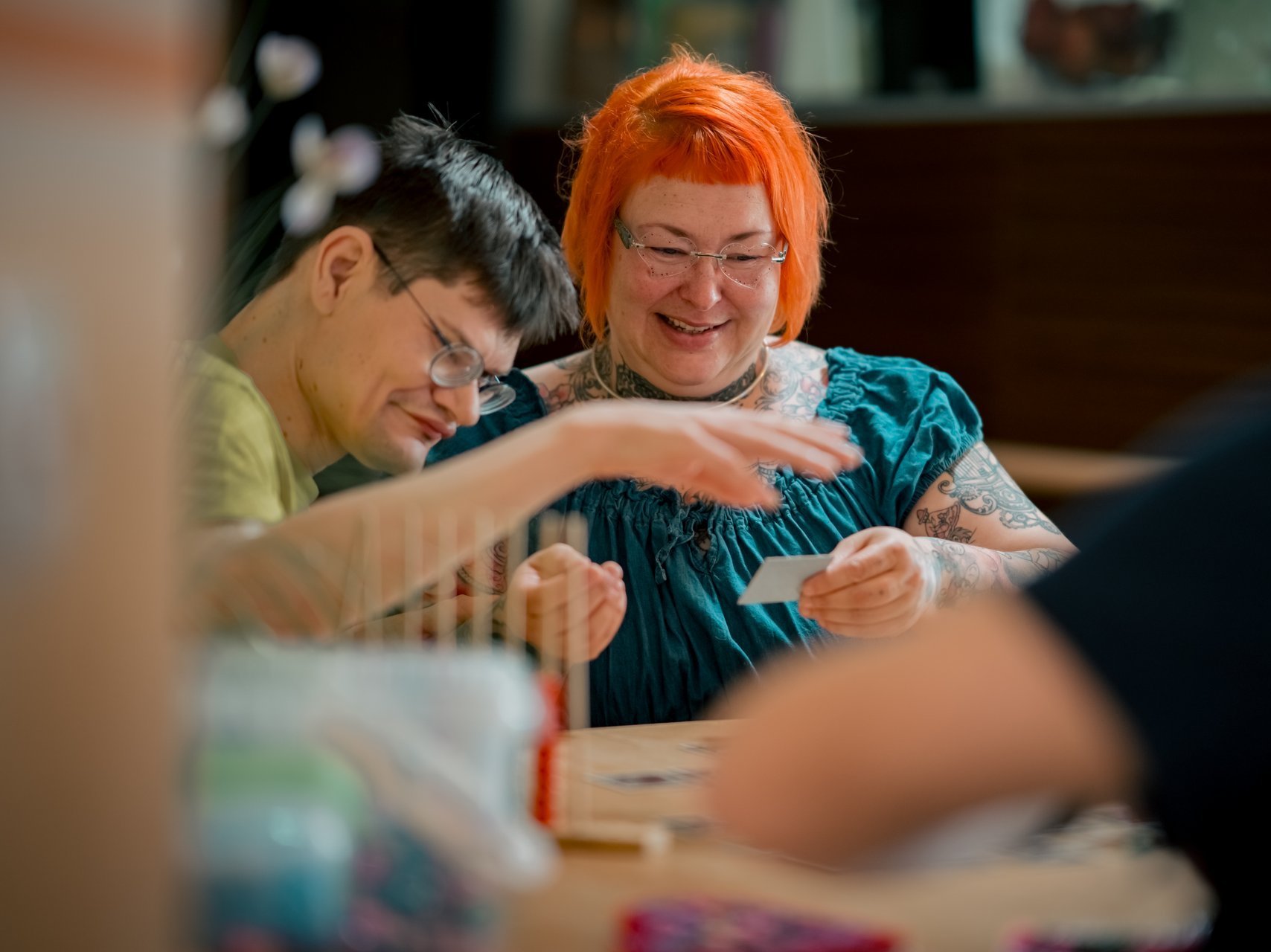 Ein Bewohner mit Beeinträchtigung und eine Mitarbeiterin lachen, während sie gemeinsam ein Brettspiel spielen.