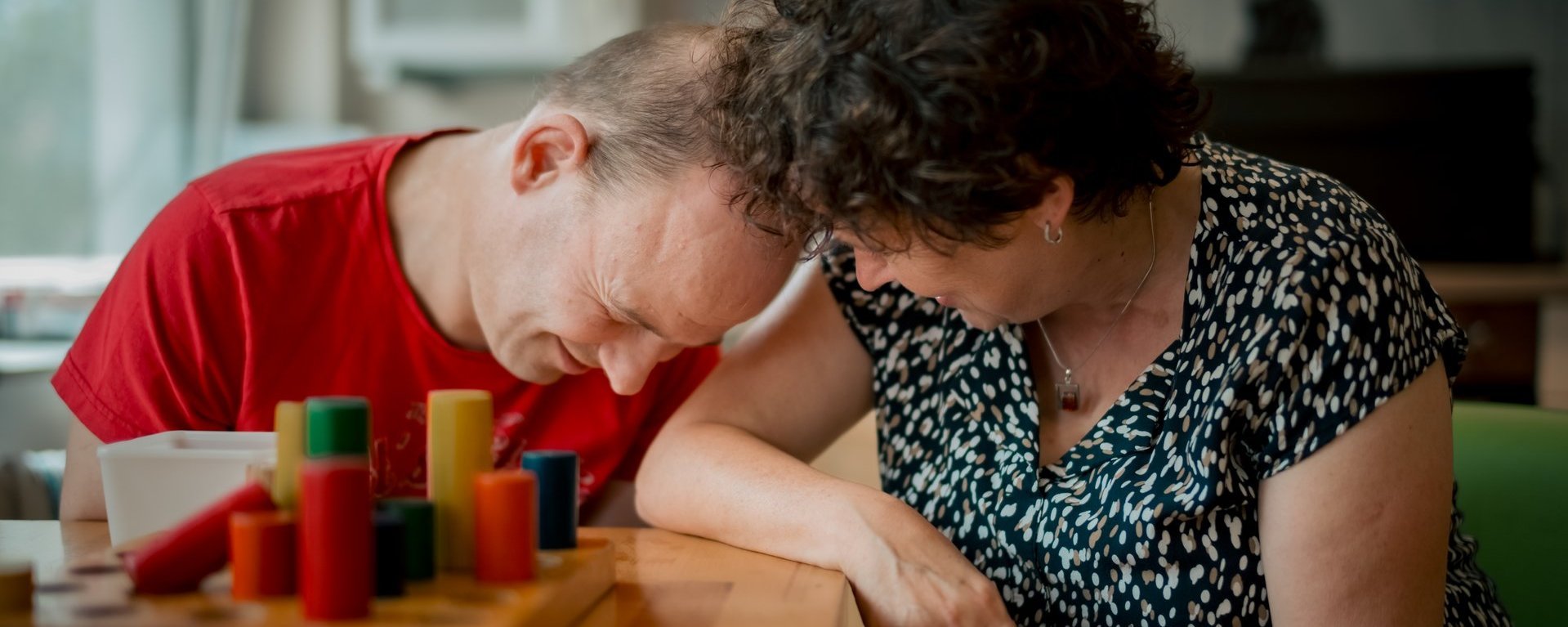 Zeit für eine Umarmung: Während dem Brettspiel drücken sich ein Bewohner mit Beeinträchtigung und eine Mitarbeiterin herzlich.