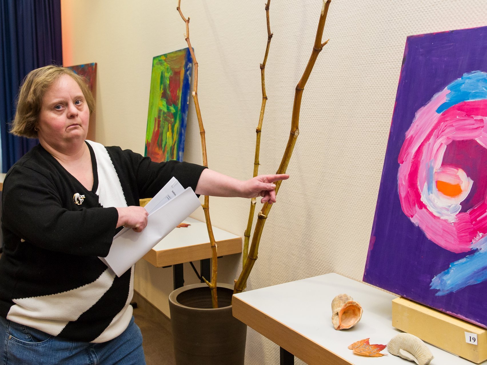Eine Bewohnerin zeigt auf ein Gemälde mit lila und blauen Kreisen 
