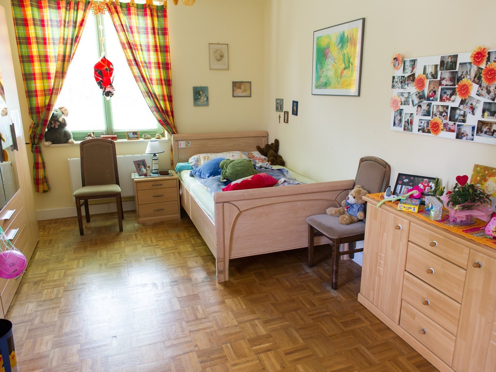 Ein gemütliches Zimmer mit Bett und Schränken und vielen Bildern