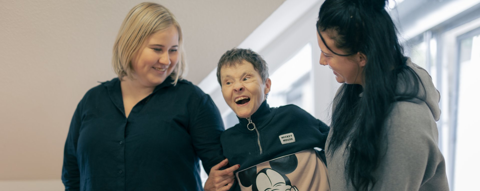Zwei Mitarbeiterinnen des Hauses Nettetal lachen zusammen mit einer behinderten Bewohnerin