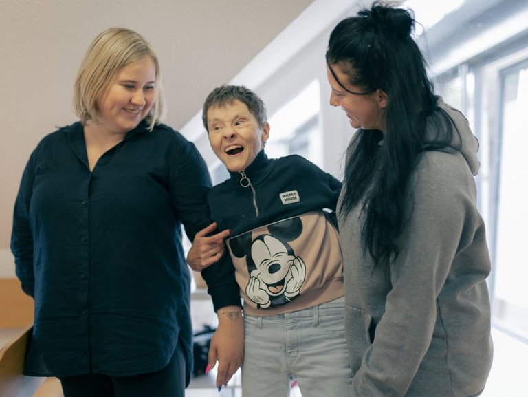 Zwei Mitarbeiterinnen des Hauses Nettetal lachen zusammen mit einer behinderten Bewohnerin